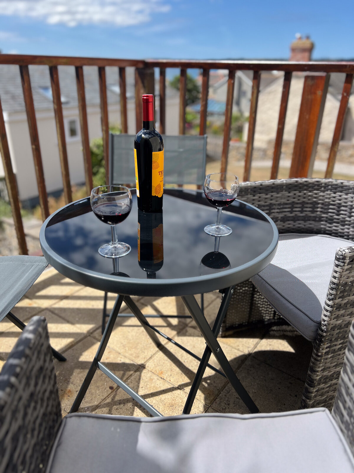 Sunny balcony with a bottle of wine and two glasses on the table