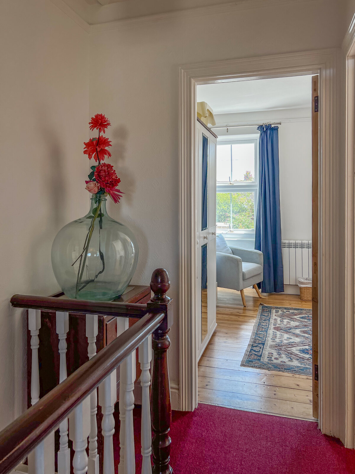 Bright landing with fresh flowers looking into a bedroom