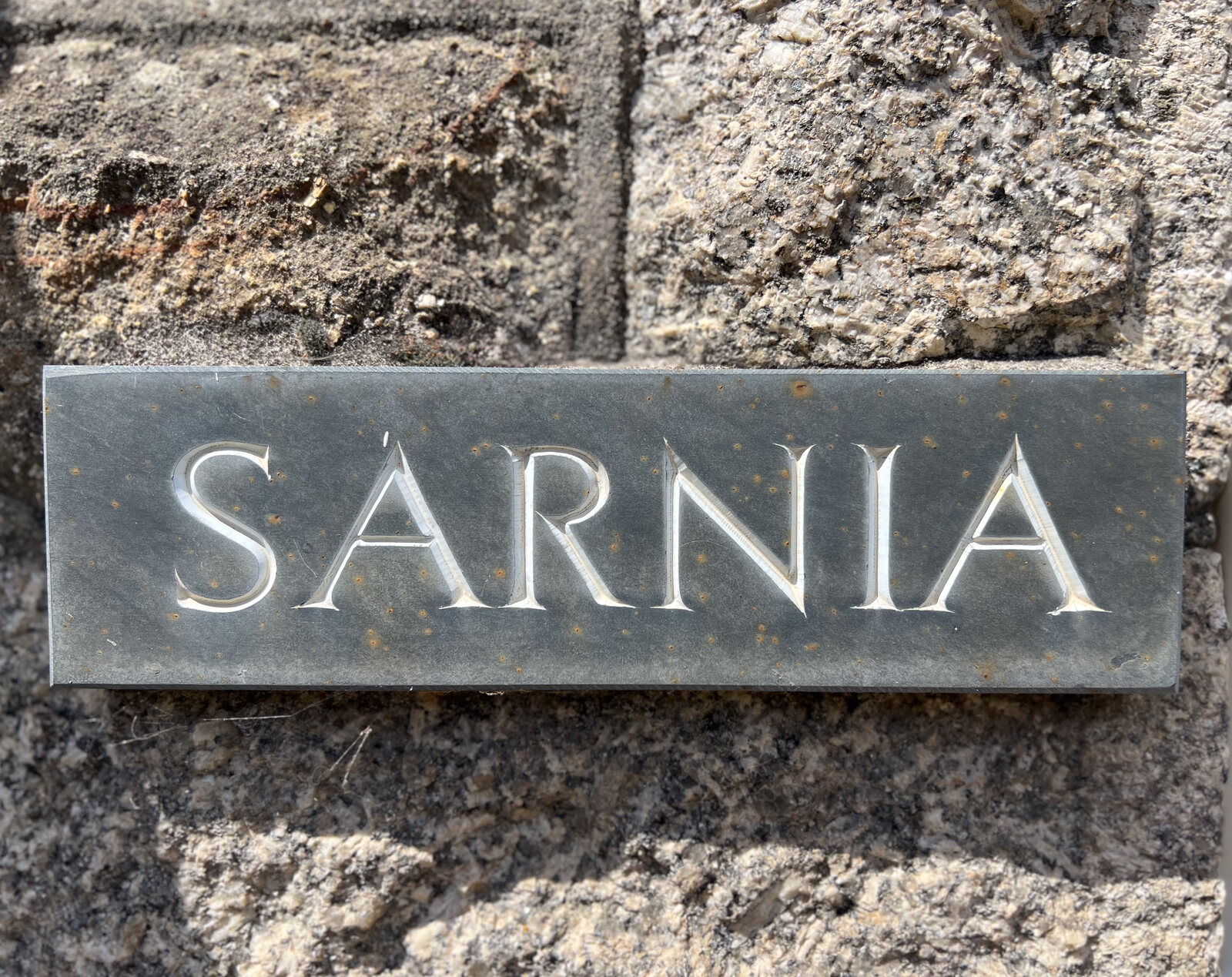 Carved granite Sarnia name sign on the cottage wall
