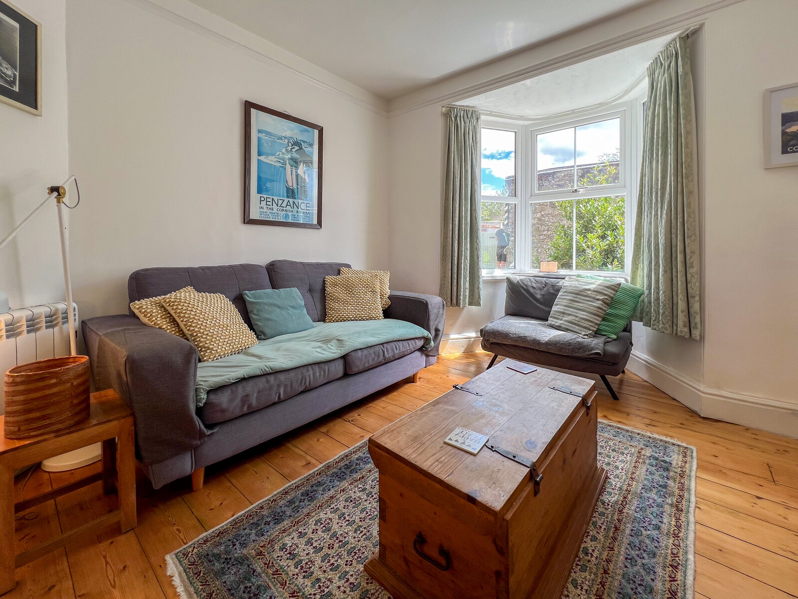 Bright sitting room with sofas, wood floors and coastal art