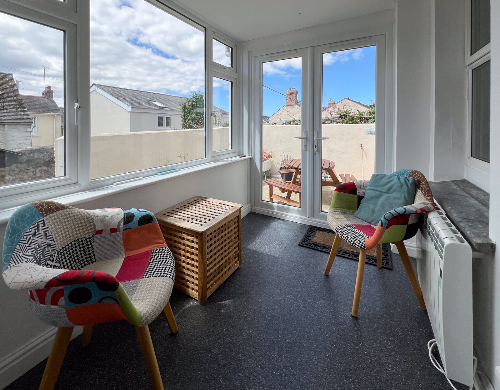 Sun lounge with colourful chairs and French doors to the patio