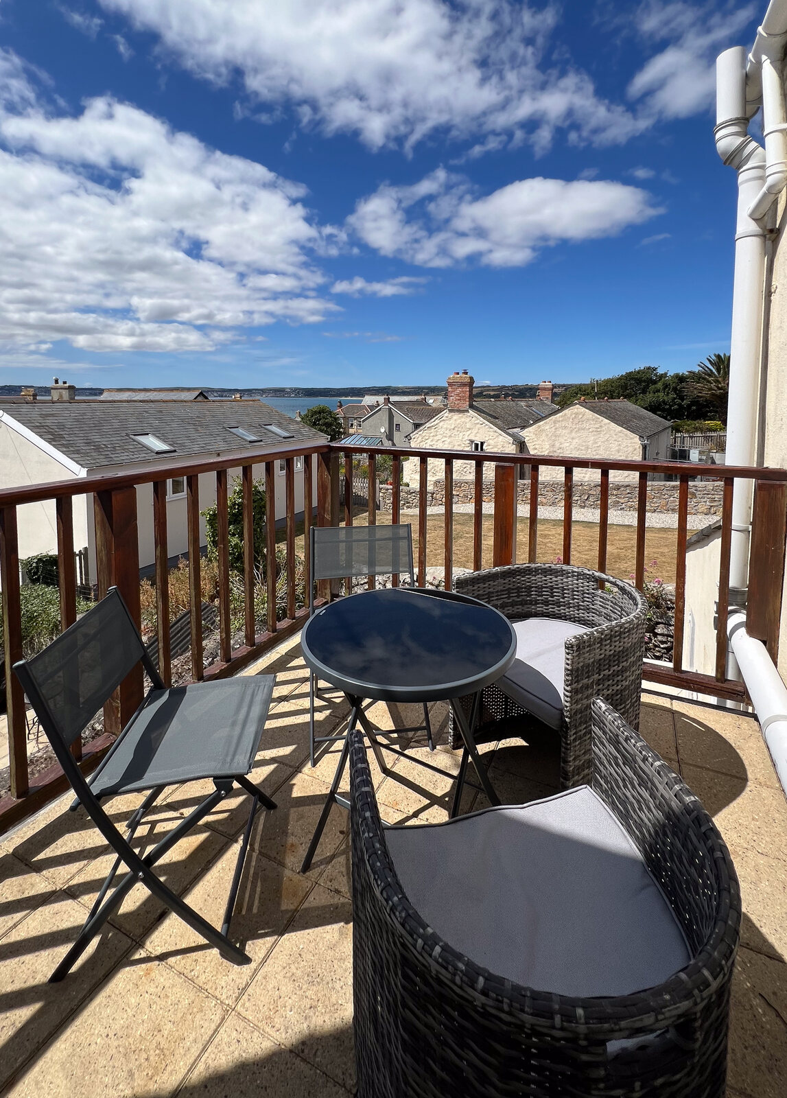 Roof terrace with rattan seating and views over the rooftops to the bay