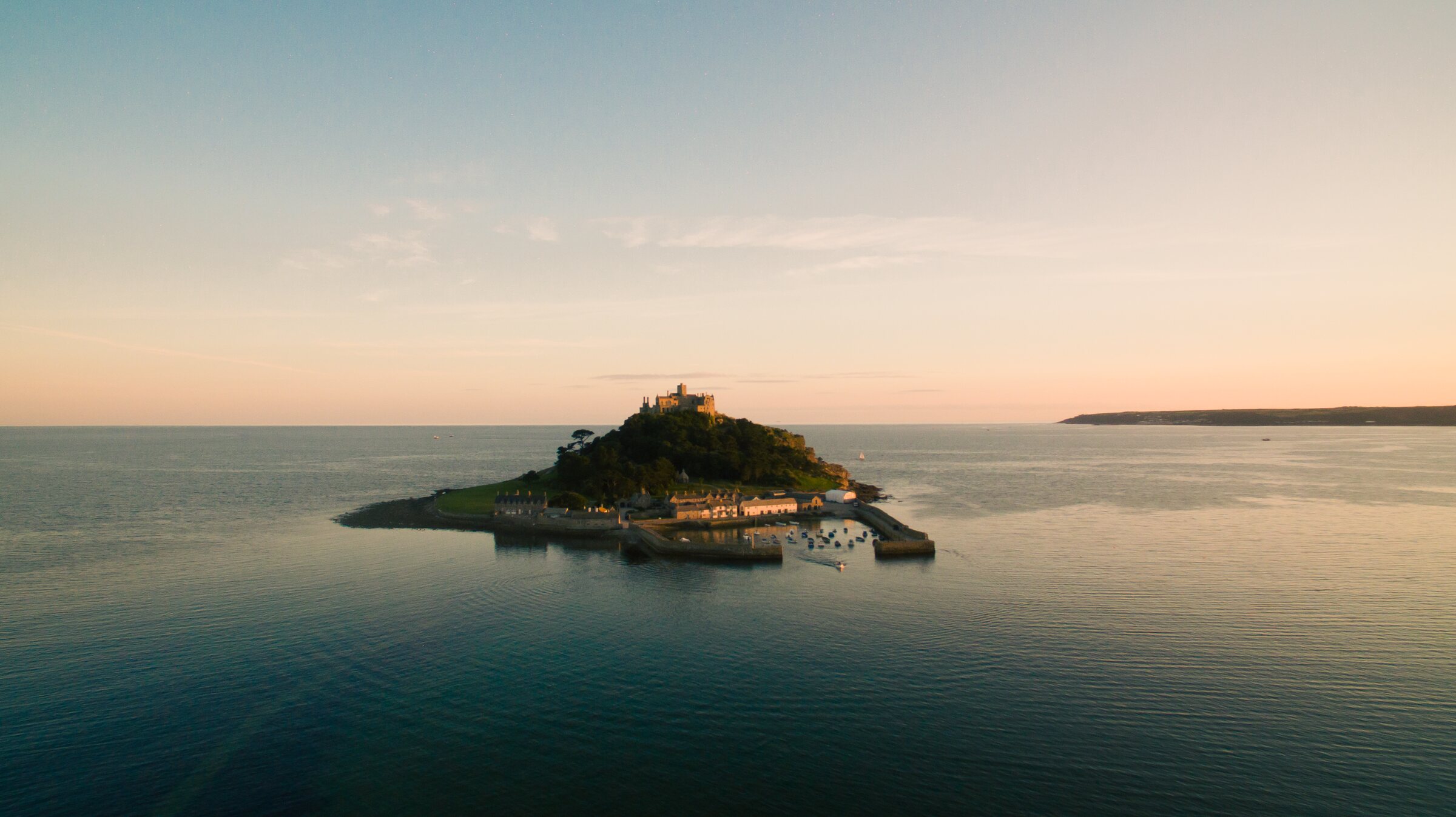 St Michael's Mount at golden hour, seen from the air across a calm Mount's Bay